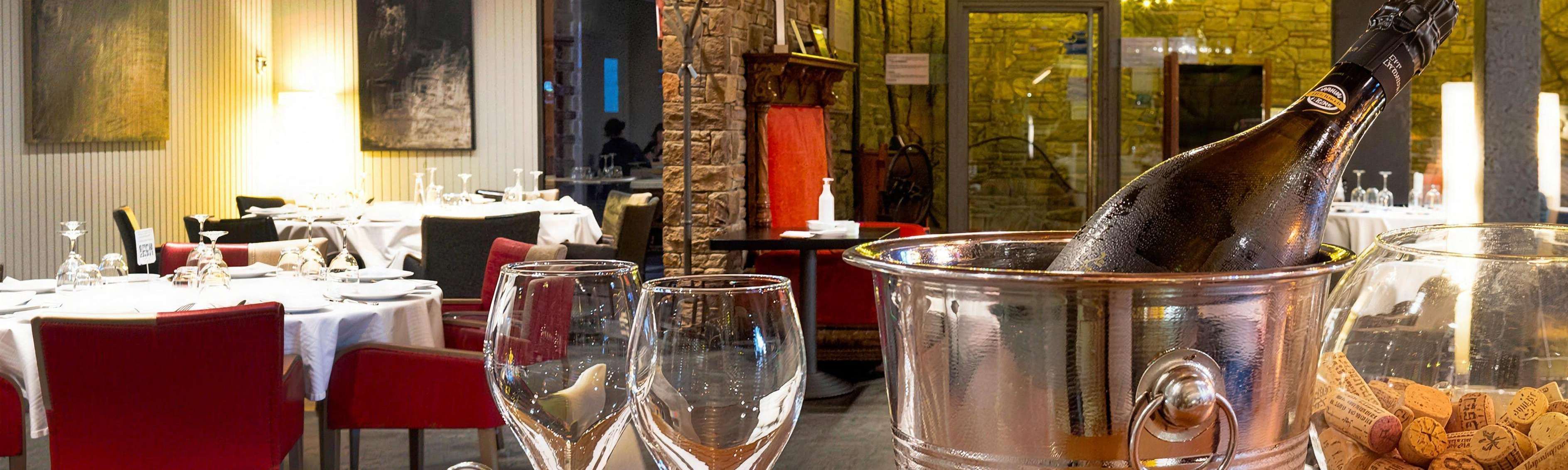 La sala del restaurant, amb les taules parades i la paret de pedra il·luminada.